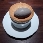A white sesame souffle under a scoop of black sesame gelato is served at Saison in San Francisco, CA.