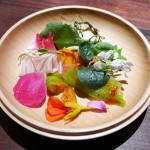 A plate of bright bitter vegetables and nasturtium honey served at Saison in San Francisco, CA.
