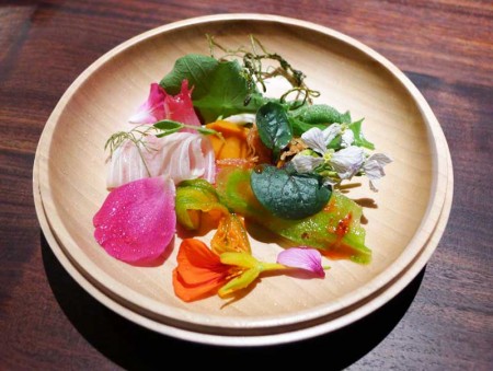 A plate of bright bitter vegetables and nasturtium honey served at Saison in San Francisco, CA.